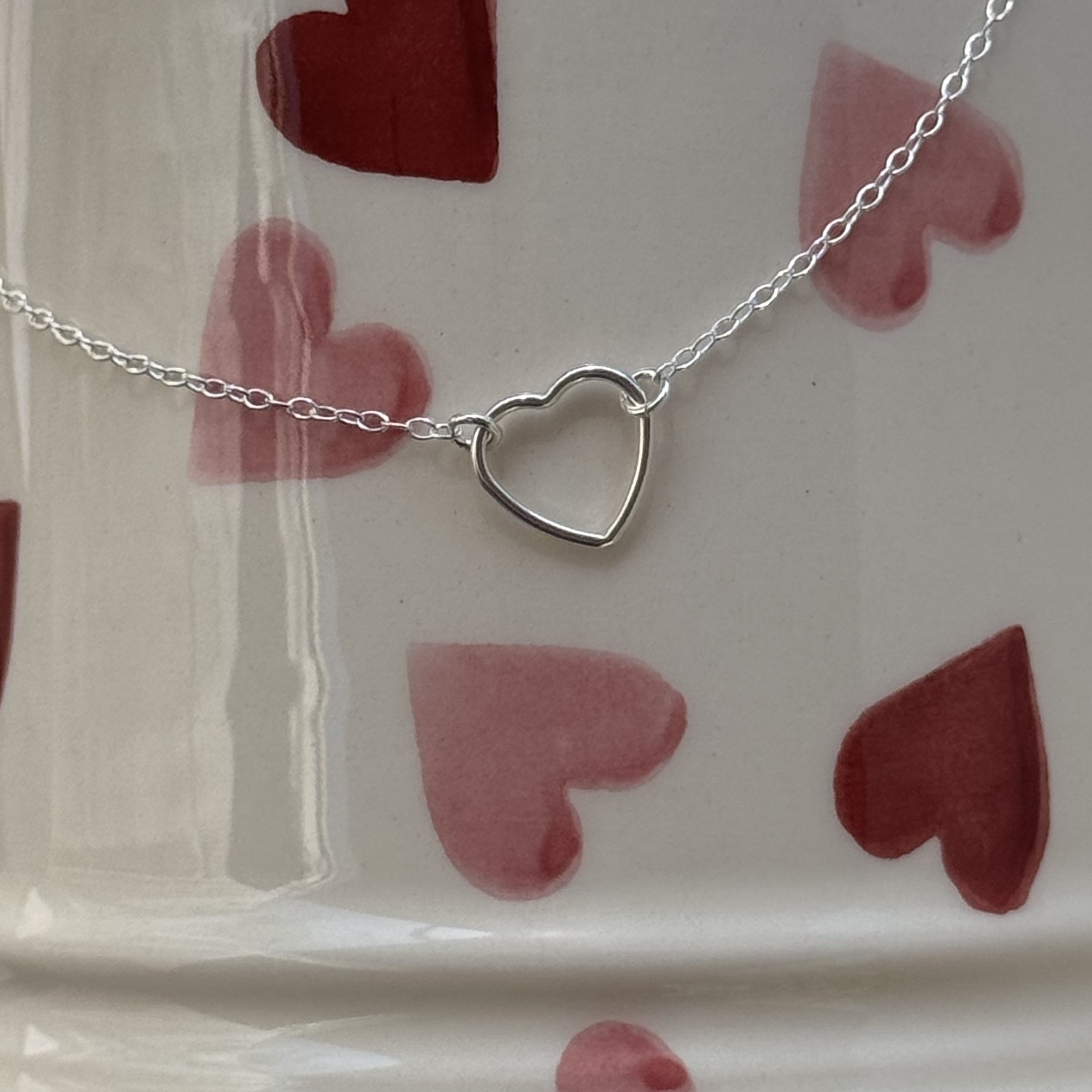 close up of dainty silver heart necklace