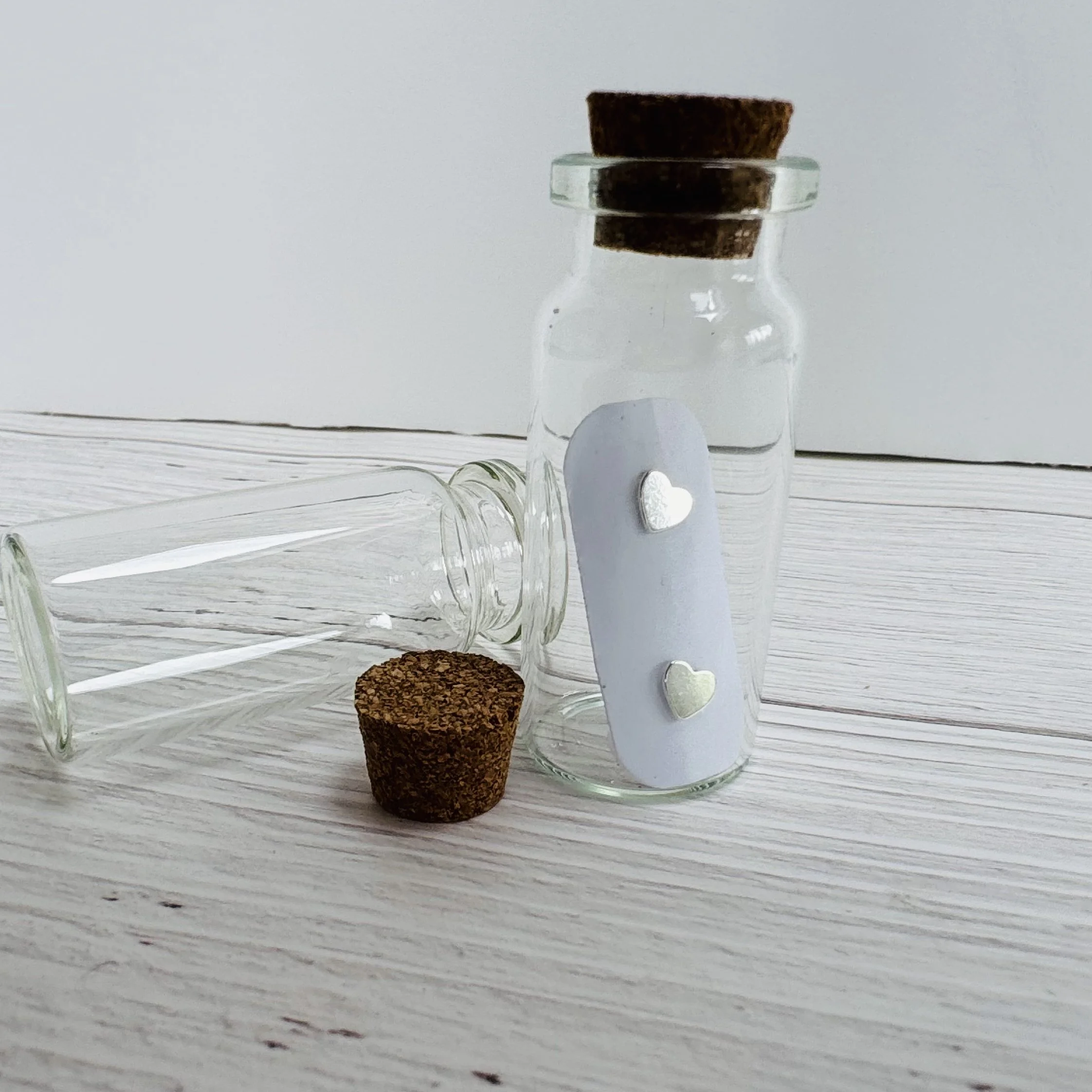 dainty silver heart studs in glass bottle