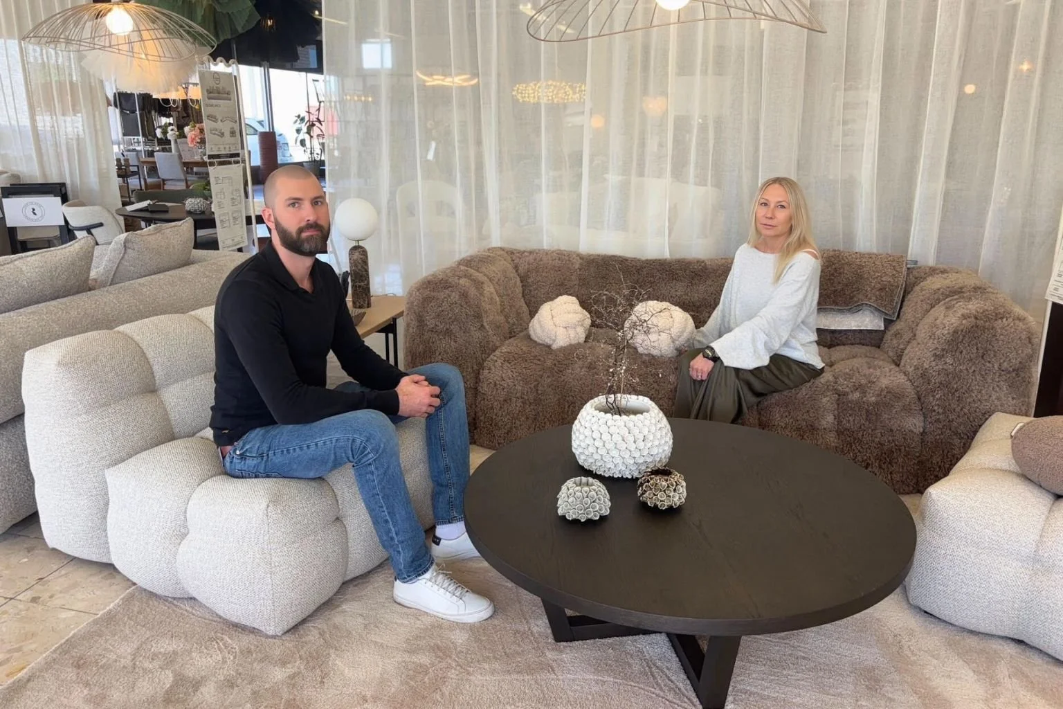 Filippa och Marcus sitter i en soffa i möbelbutiken Maessing Interiör