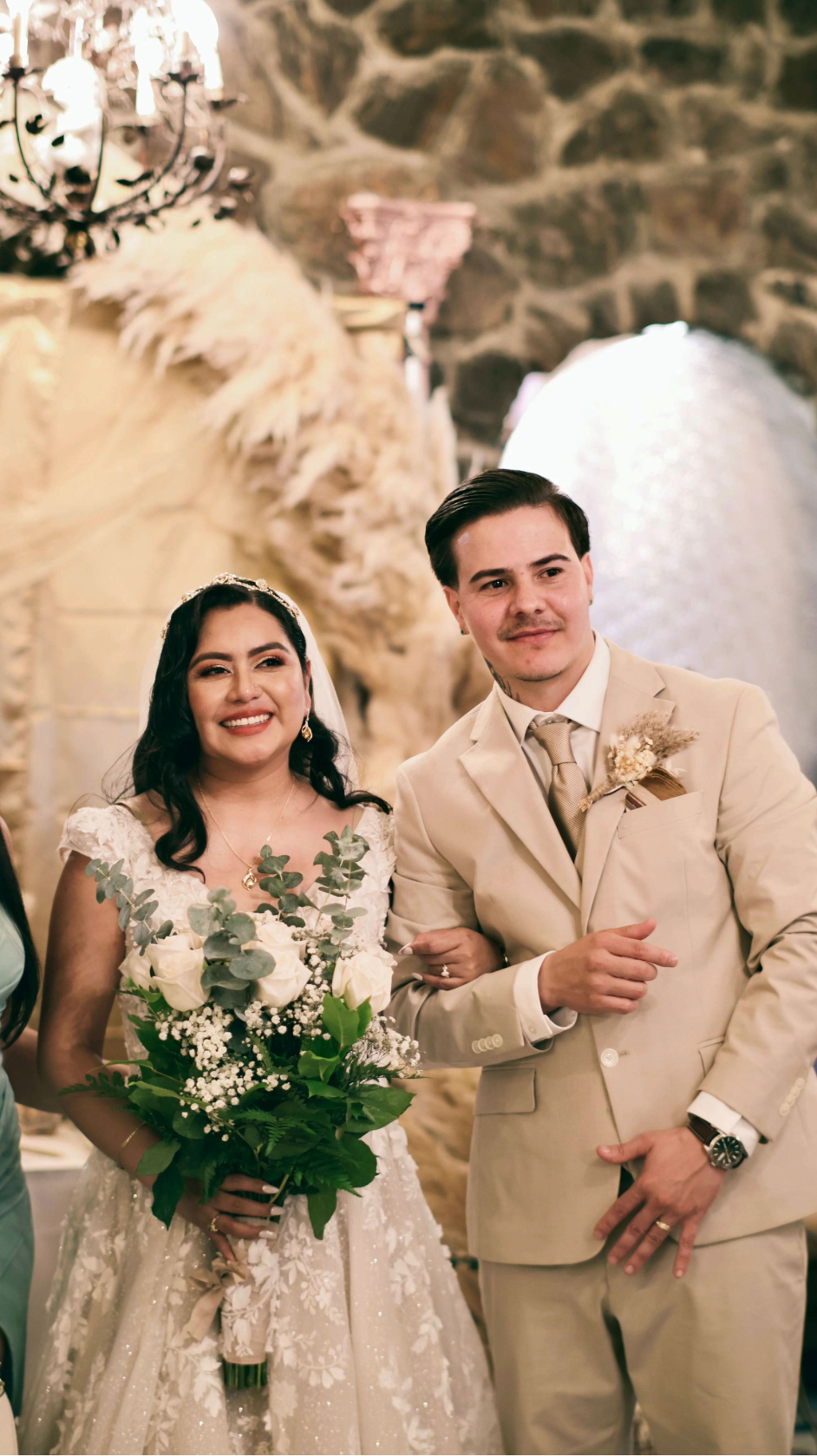 Bride and groom posing together with bouquet and reception décor.