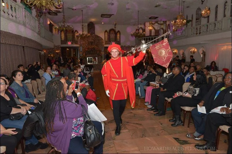 Costumed trumpeter making a ceremonial entrance through a seated banquet audience.