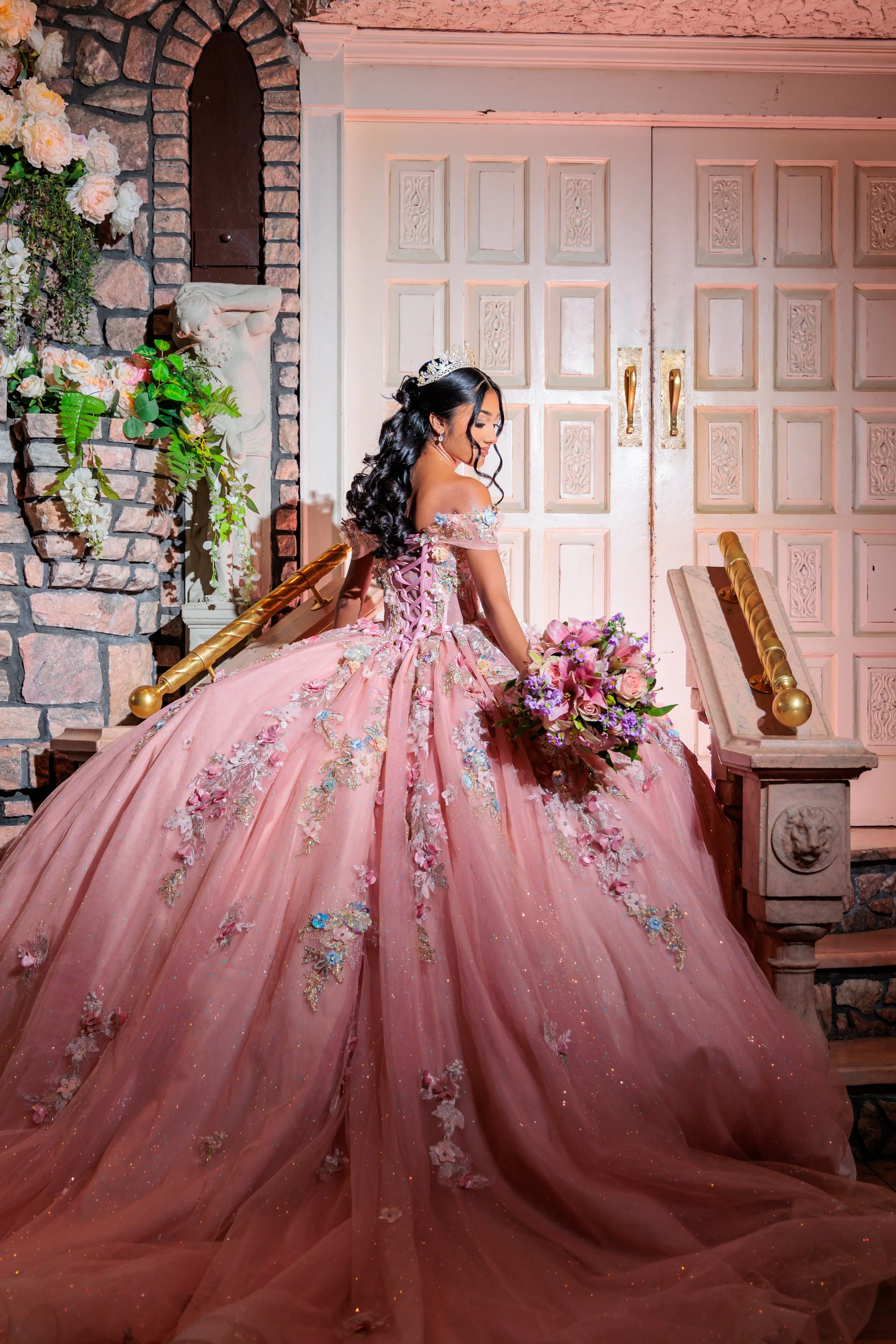 A Sweet 16 birthday girl in a pink flower dress is stopping for a photo op after entering into the room.