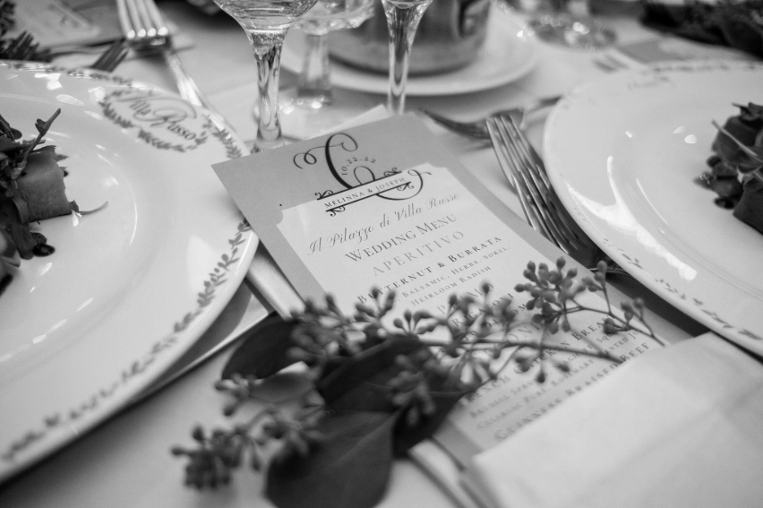 Custom wedding menu and place setting with greenery at a Villa Russo wedding reception.