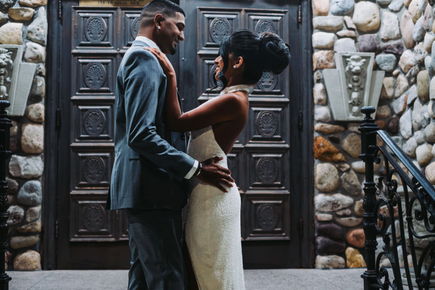 Bride and groom posing together in front of the carved wooden doors at Villa Russo.