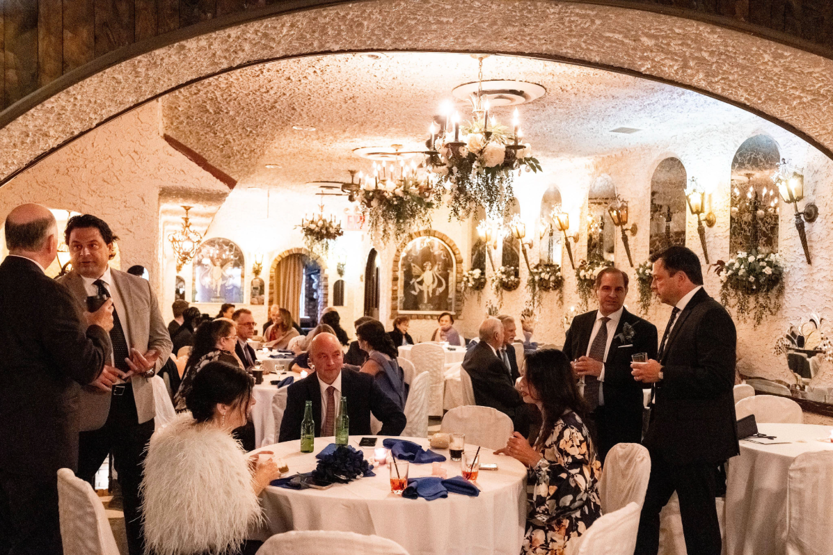 Intimate wedding reception room in Queens, New York, set with round guest tables, chandeliers, floral décor, and warm architectural details.