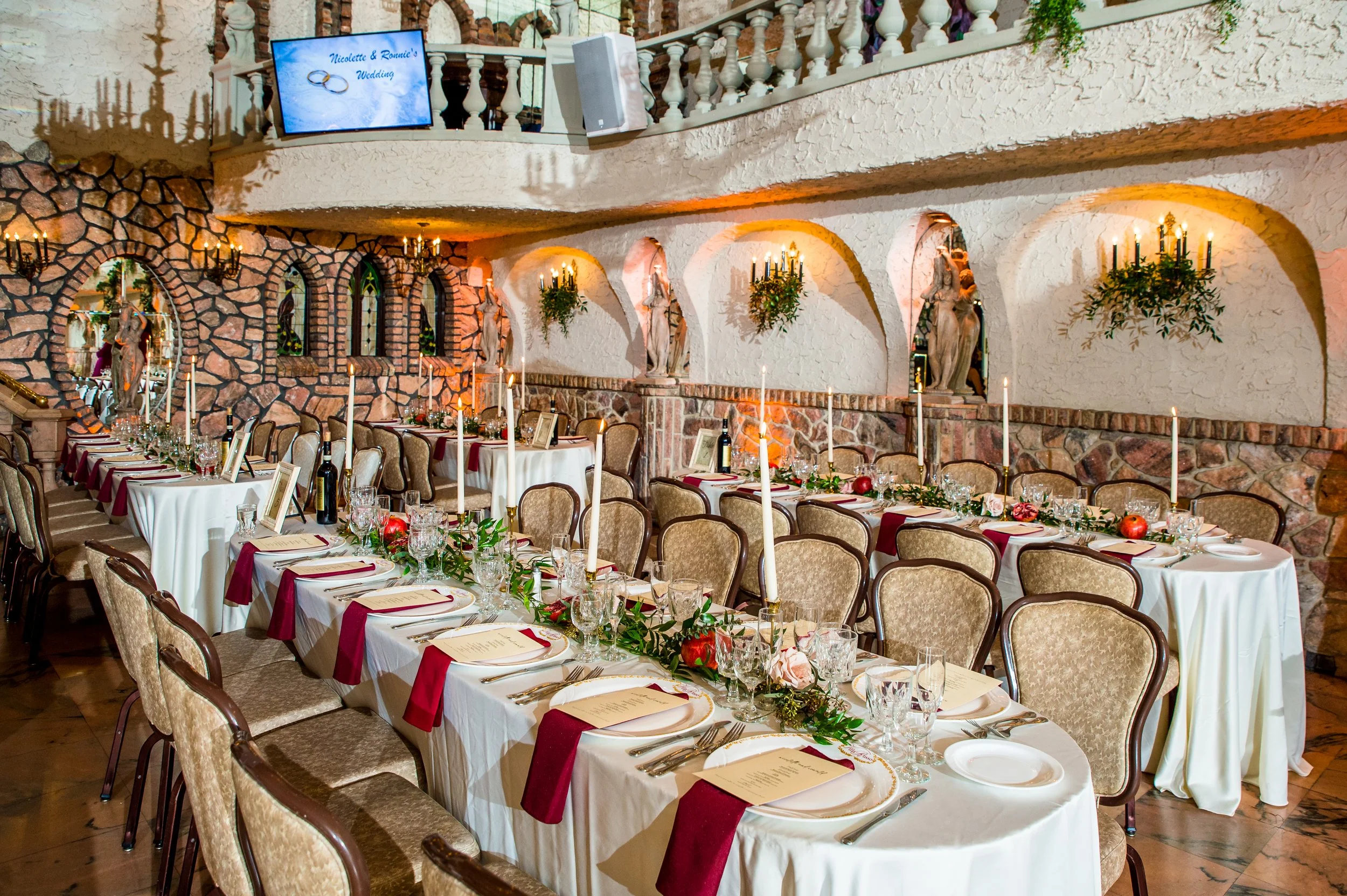 A wedding setup displaying the tables where guests will sit, with adornments and candles running along the center of each table. The wedding is hosted in one of the rooms inside Villa Russo.
