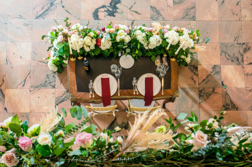 Overhead view of a sweetheart table decorated with lush florals and burgundy place settings at Villa Russo.