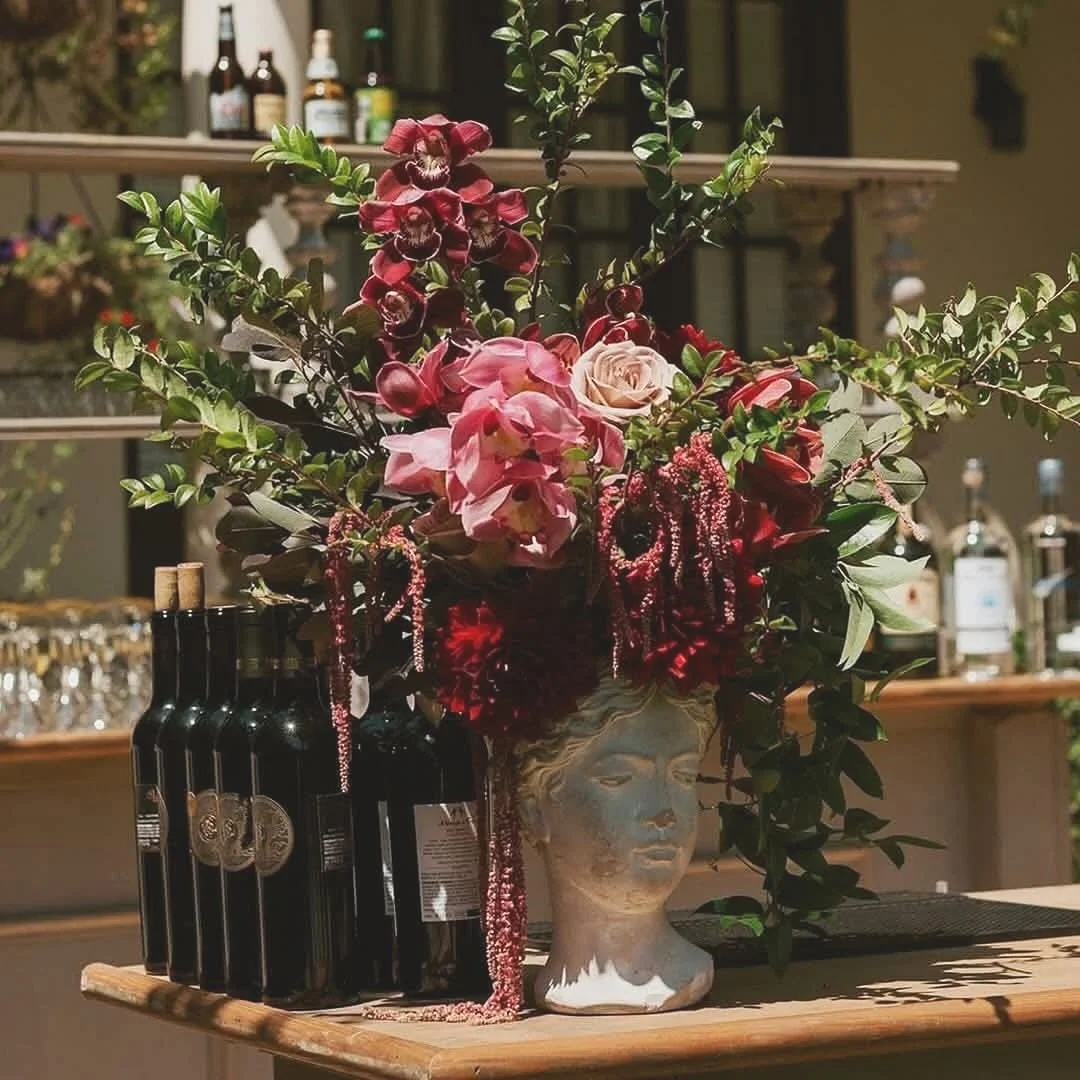 A floral arrangement in a ceramic bust vase featuring pink roses.