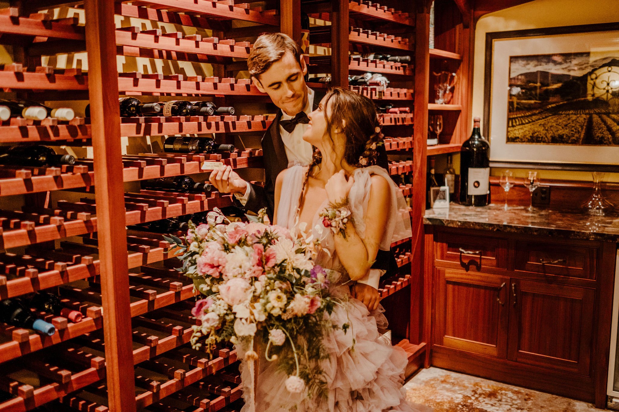 A bride and groom in the wine cellar, with the groom opening a bottle of wine, getting ready to enjoy their wine cellar intimate moment.  Put your plaque up and come back for your aniversary at the Julia Morgan Redwood Grove.