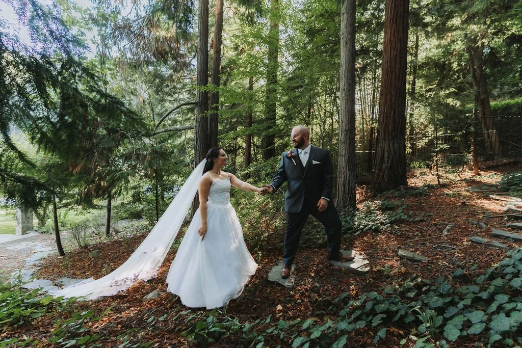 Bride and groom holding hands in a forest setting during their wedding photoshoot at the Julia Morgan Redwood Grove property.