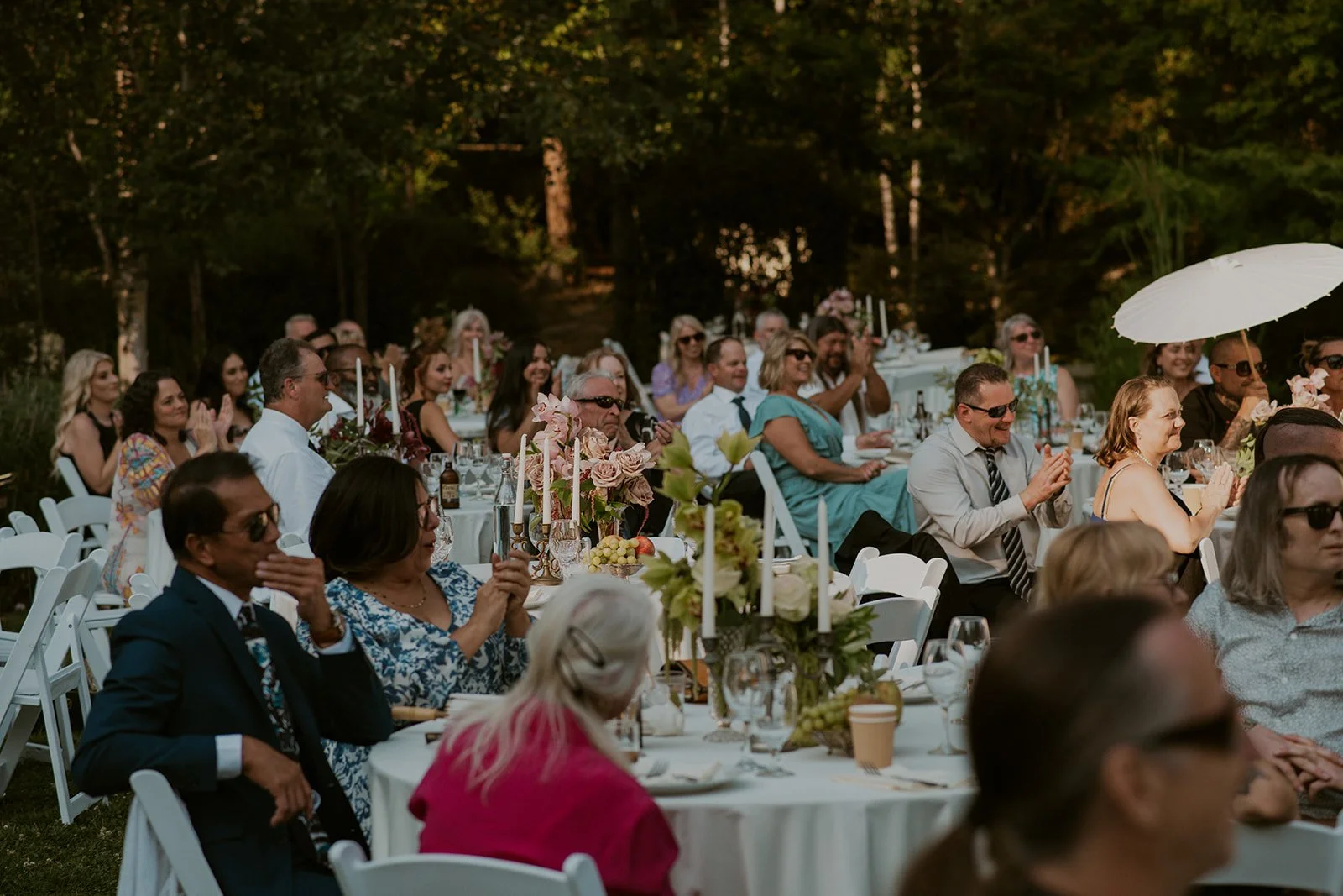 Outdoor wedding reception with guests seated at decorated tables.