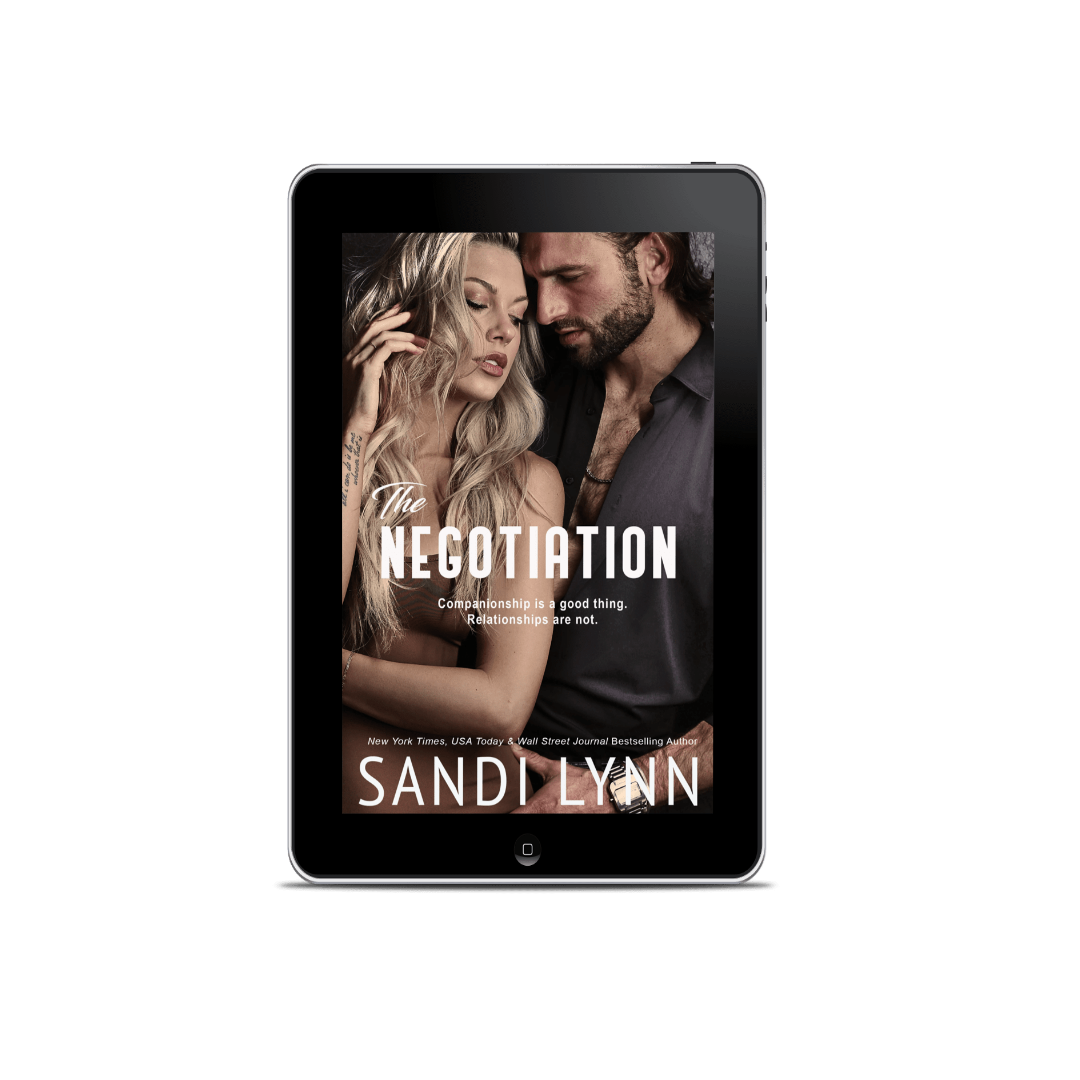 A digital tablet displaying the cover of a book titled 'The Negotiation' by Sandy Lynn, featuring a photo of a man and woman in an intimate pose.