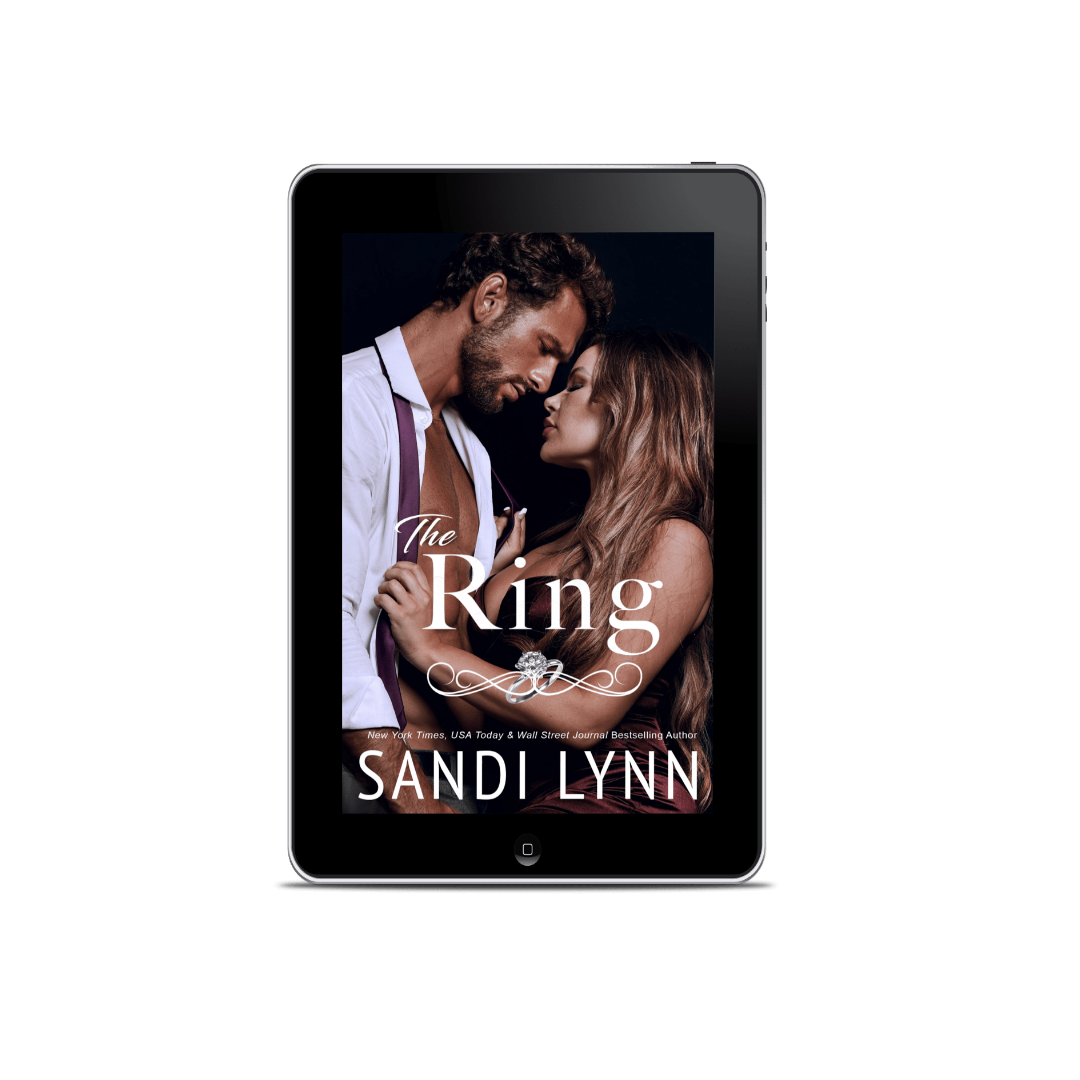E-book cover titled 'The Ring' by Sandi Lynn, featuring a man and woman close together in a romantic pose, on a tablet with a laptop behind it.