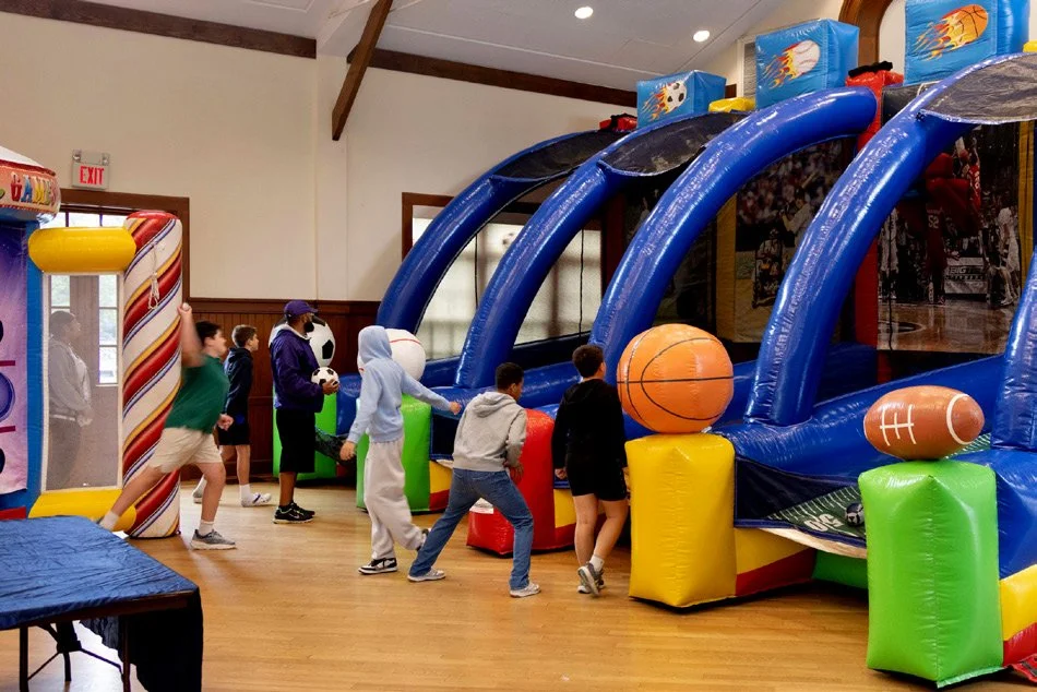 Kids playing inflatable basketball and football games in the church hall