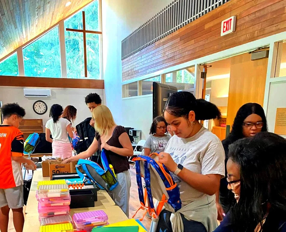 Youth filling backpacks with school supplies