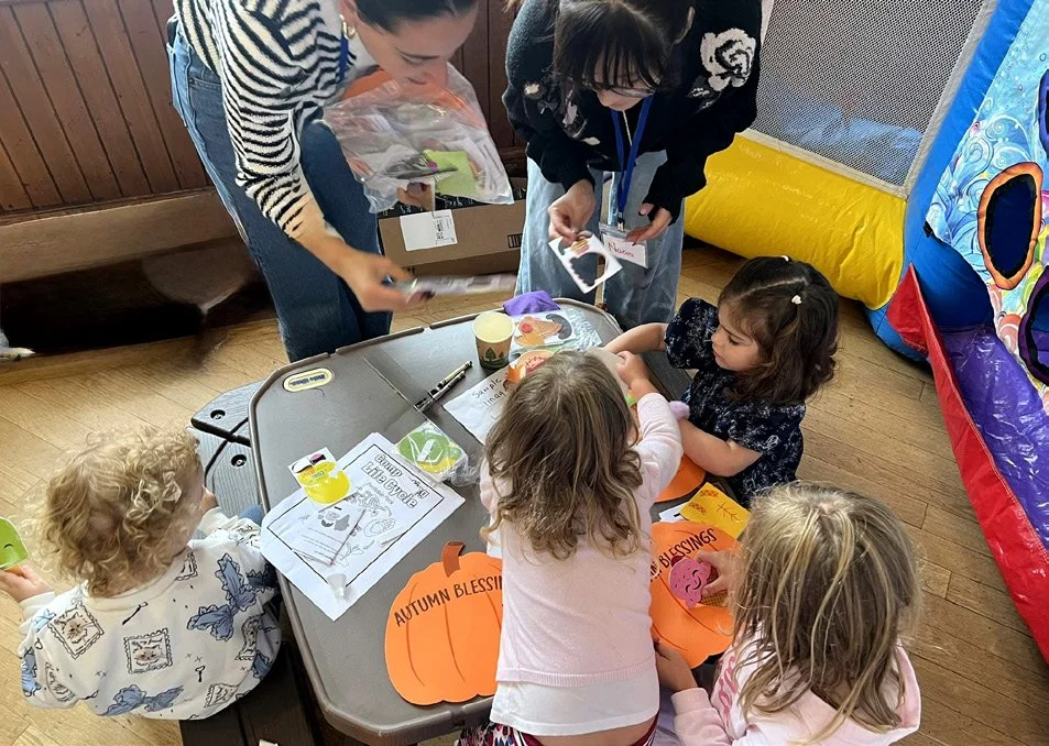 Young kids working on a pumpkin craft around a table