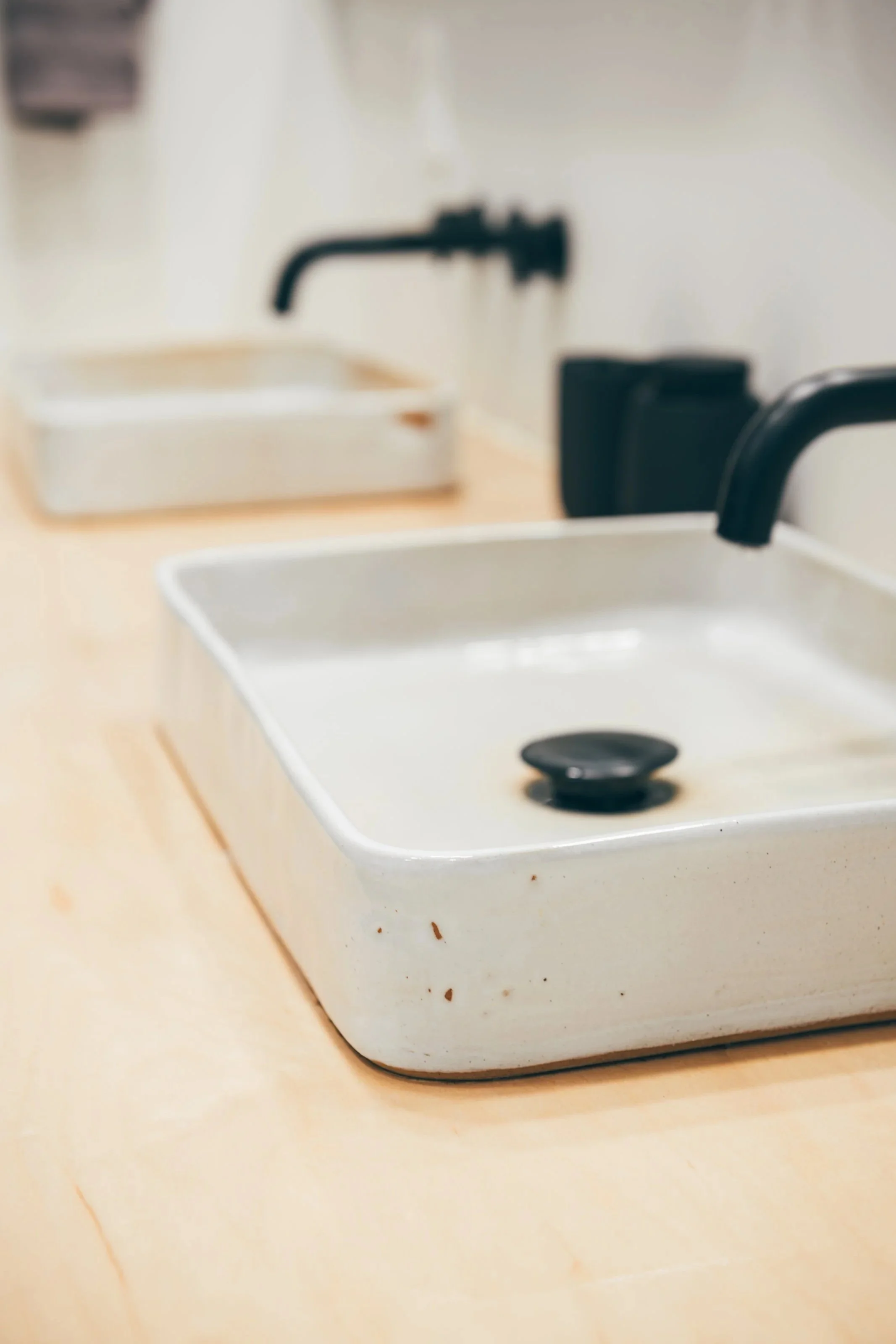 Close-up of a white rectangular dish containing a black suction cup mechanism, placed on a light wooden surface, with a blurry background.