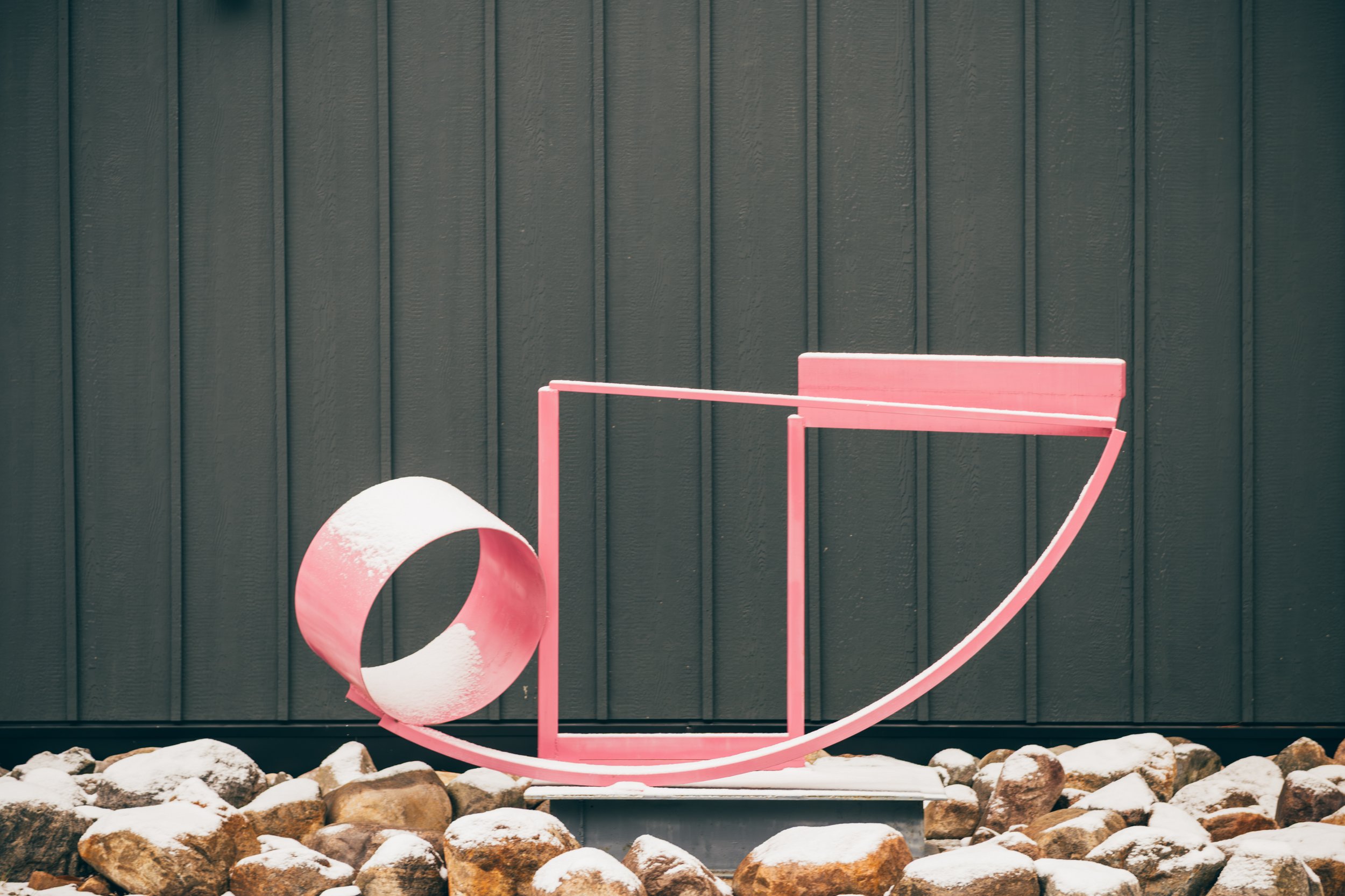 A painted metal sculpture outdoors on a pedestal