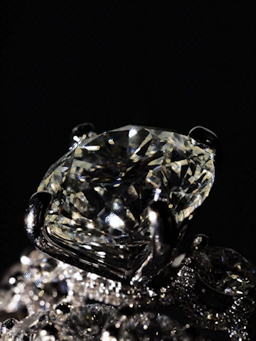 Close-up of a diamond ring with a large center stone and smaller surrounding stones, set in a dark setting.