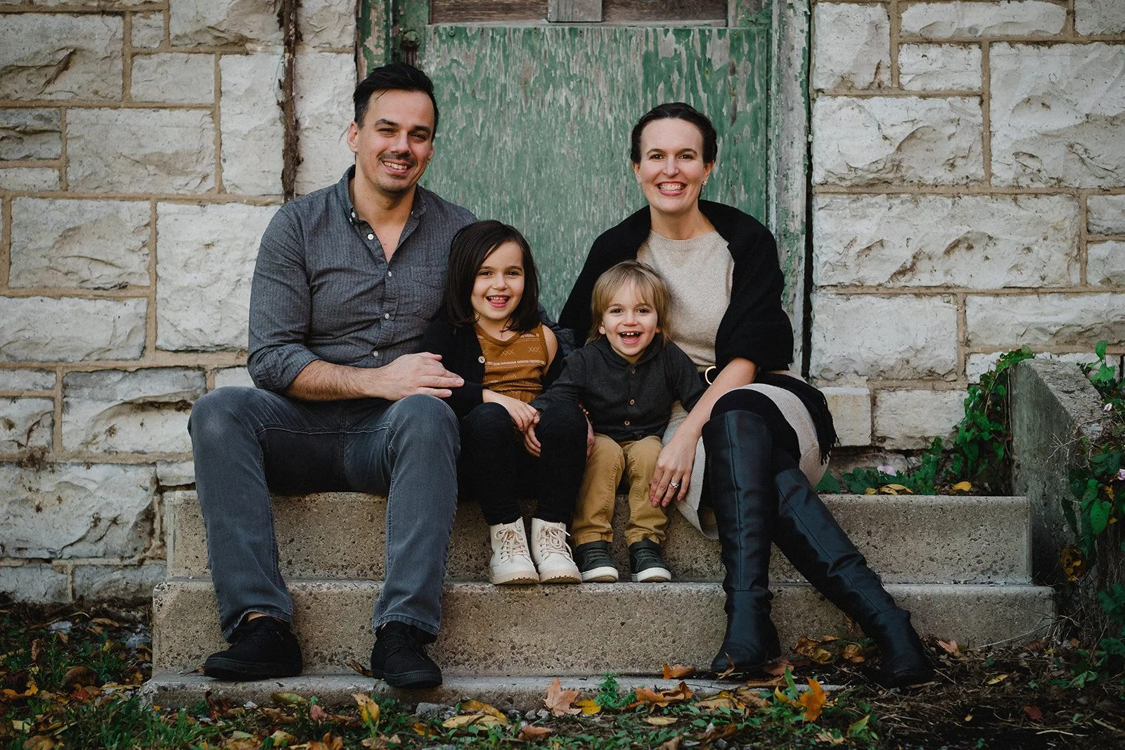 A happy family of four sitting on a step, smiling and enjoying their time together.