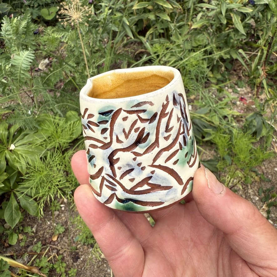 pot2946 - Cream jug withembracing chaps and yacht. Caramel glaze inside.