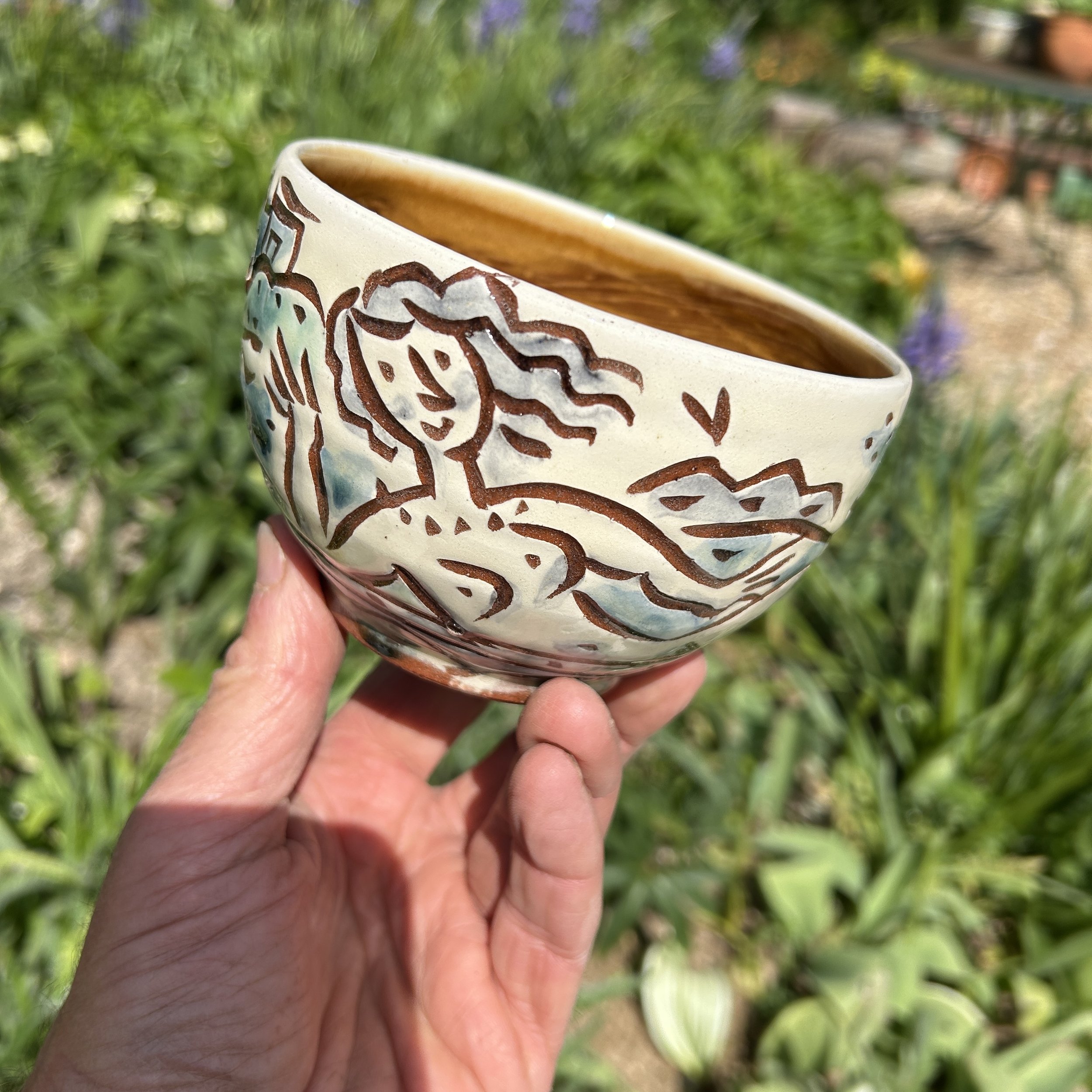 pot2856 Cereal bowl with sunbathing couple and seascape. Caramel coloured glaze inside.