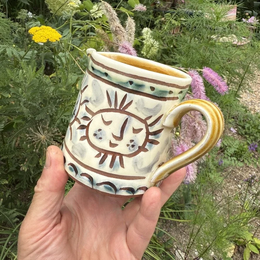 pot3040 - Milk jug with smiley sunfaces. Caramel coloured glaze onside and on handle.