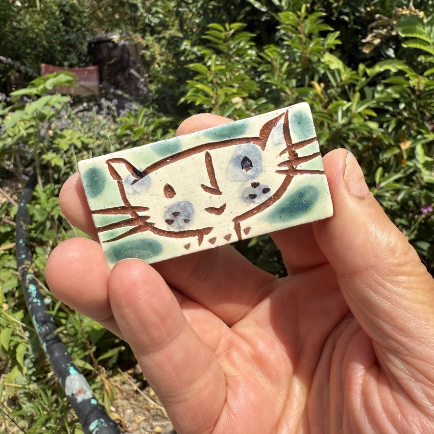 pot2976 Small rectangular tile with cat face.