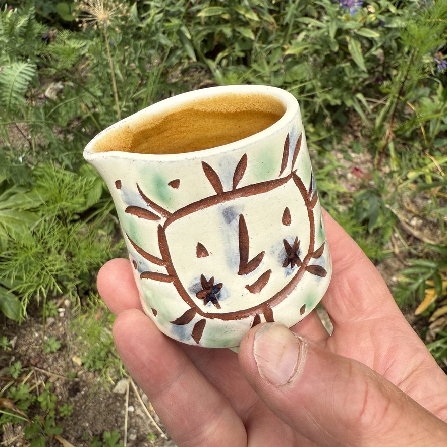 pot2941 - Cream jug with sunfaces. Caramel glaze inside.