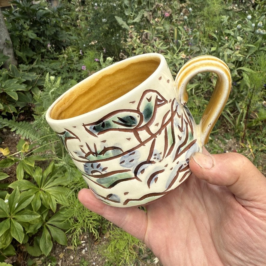 pot2952 Slipware large tea mug with women and birds. Signature on base. Caramel glaze on handle and inside.