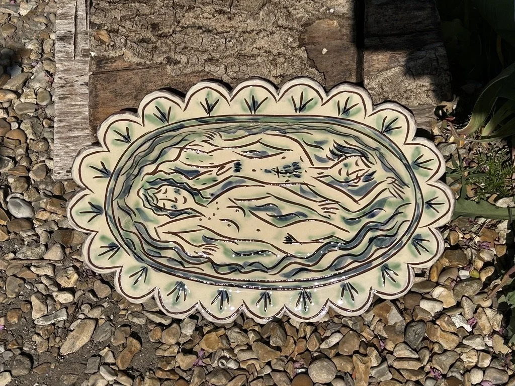 pot3058 - Scalloped platter with swimmimng couple, scalloped edge. Hanging loop on reverse.