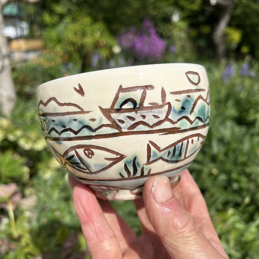pot2855 Cereal bowl with seascape and fish border. Caramel coloured glaze inside.