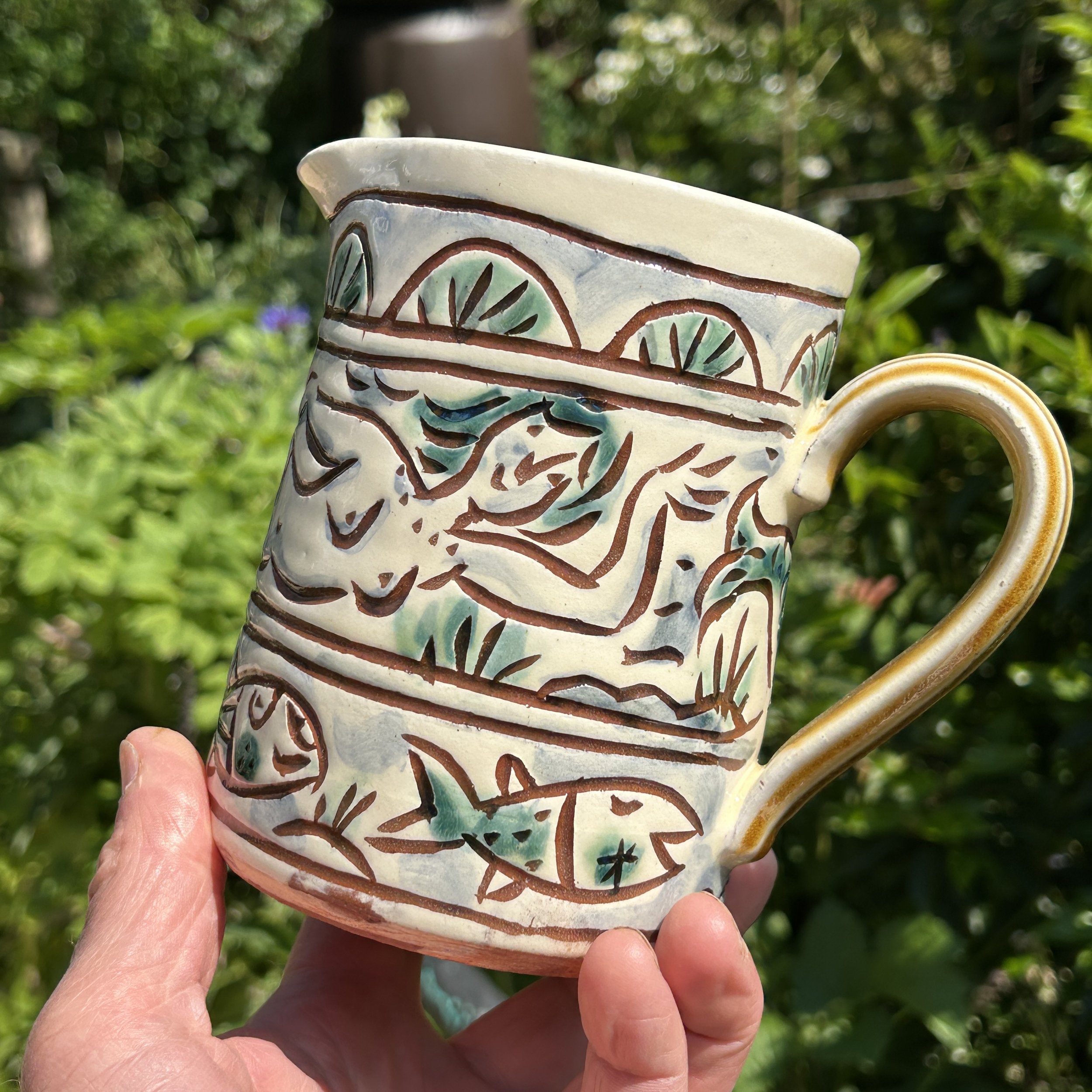 pot2903 - Flower jug with mermaids and fishes, shell border. Caramel coloured handle and inside.