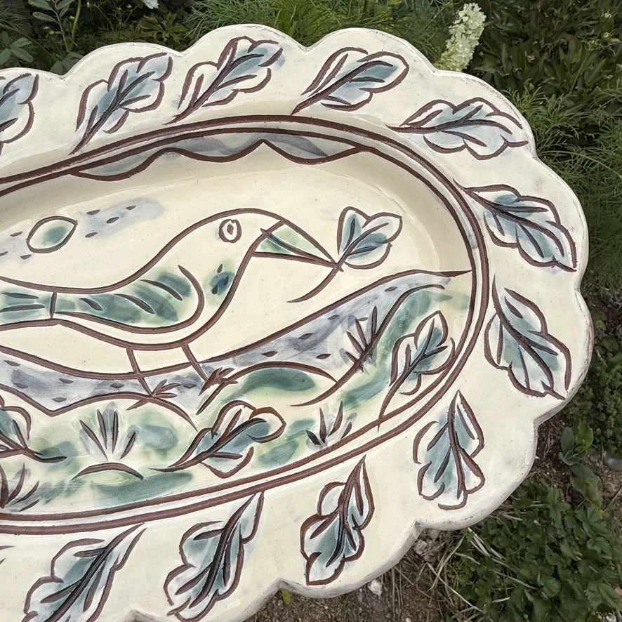 pot3034 - Scalloped platter with bird and leaf, leaves border and hanging loop on back.