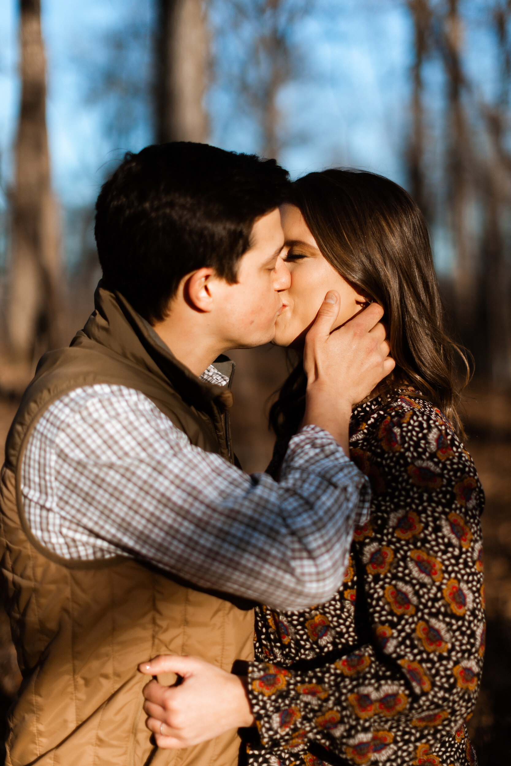 Couple Kissing In Woods During Family Farm Winter Engagement Photo Session