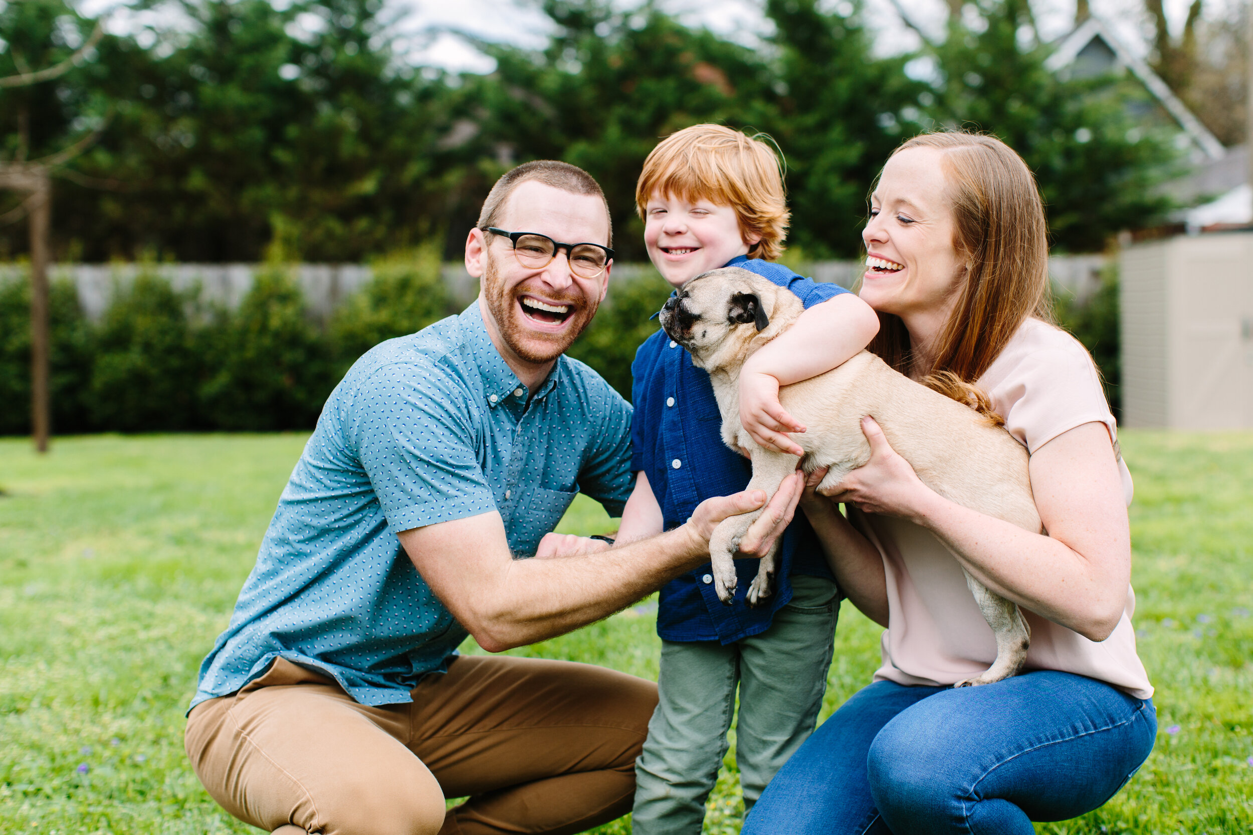 Family Snuggling Pug Dog During Knoxville Family Photos in Front Yard And Front Porch