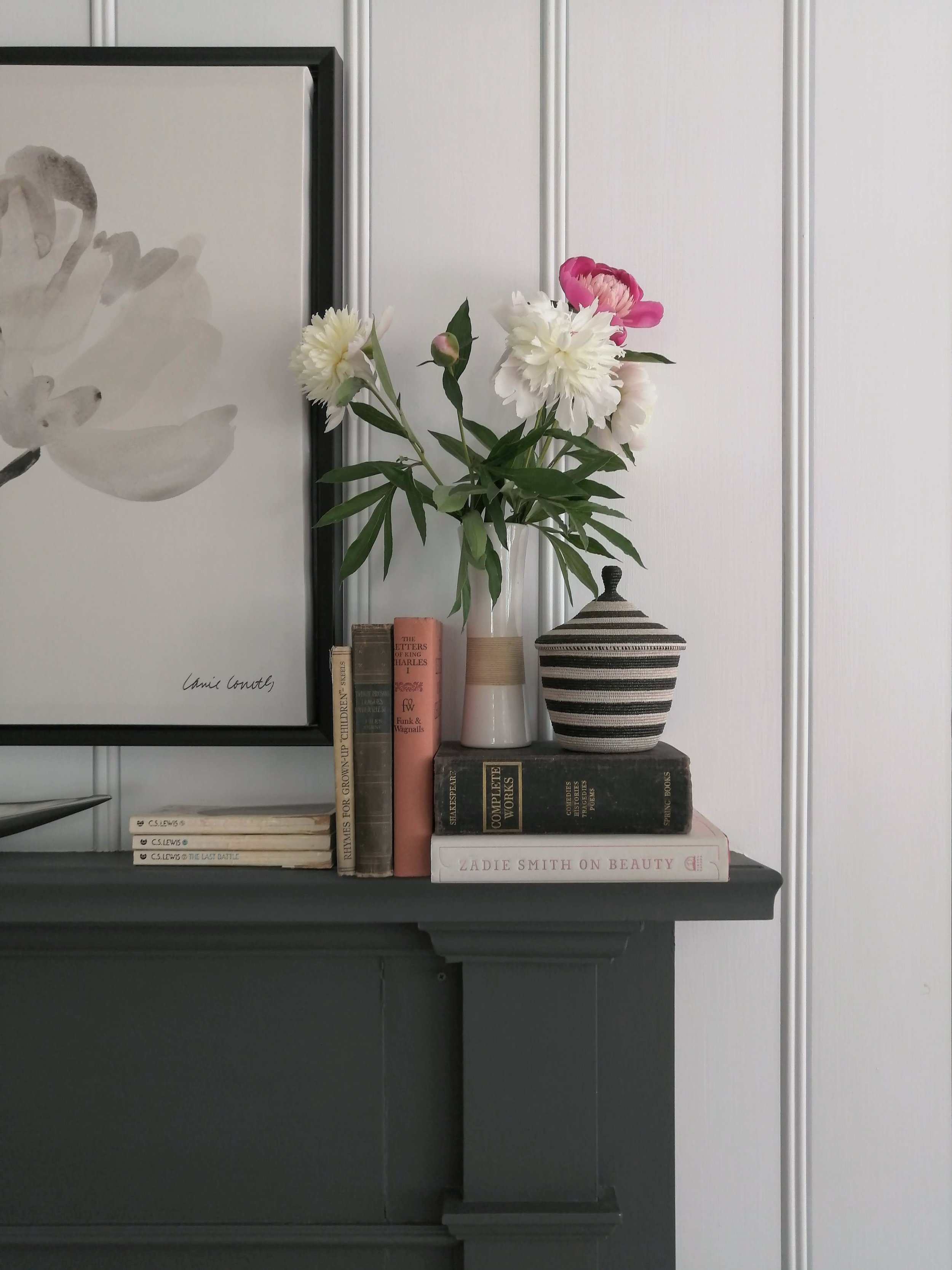 Fireplace styling, books and flowers, dark gray mantle on white wall - Cheryl Lee Interiors
