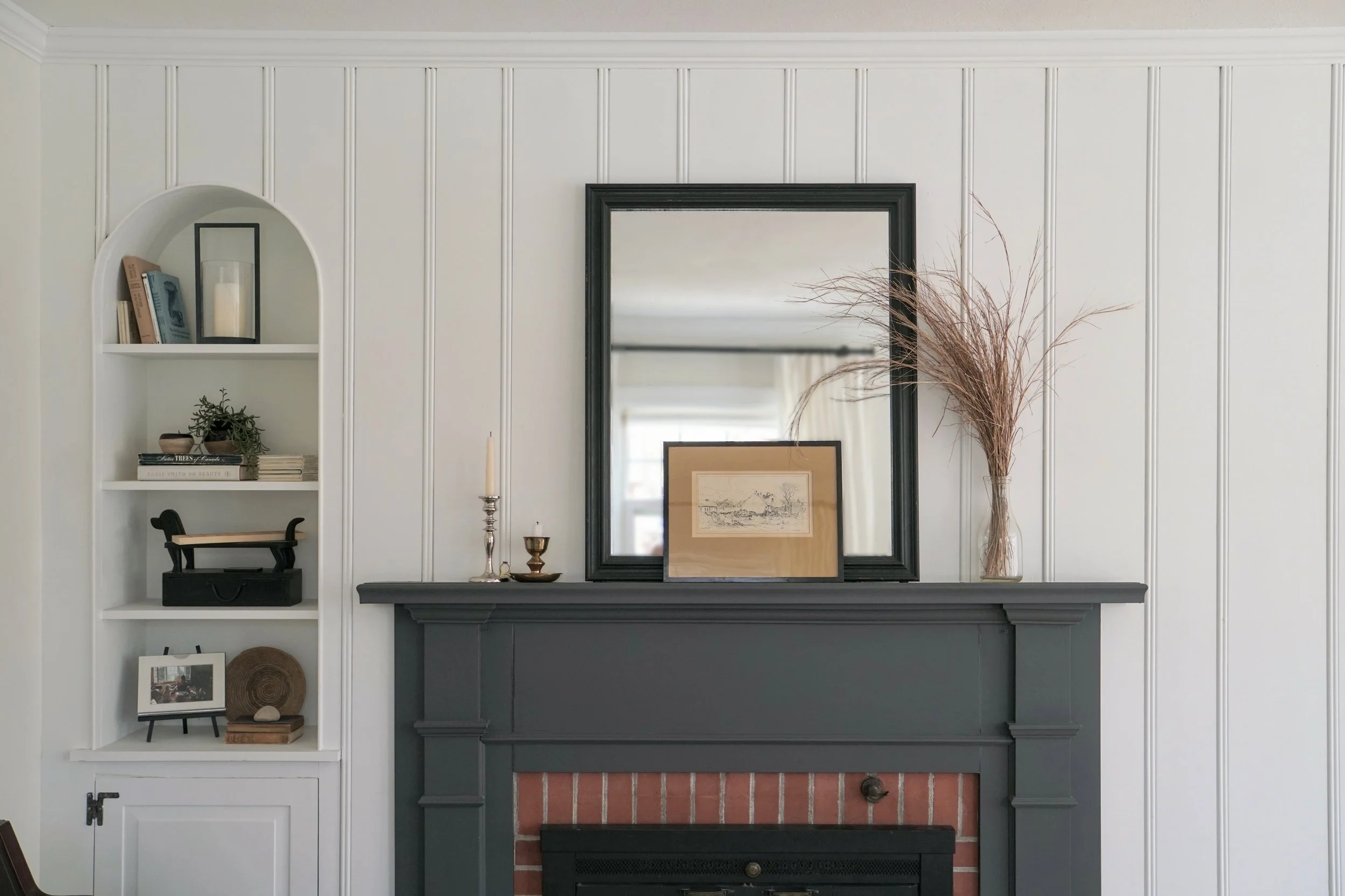Fireplace and small arch built-in styling, dark gray mantle with red brick surround - Cheryl Lee Interiors