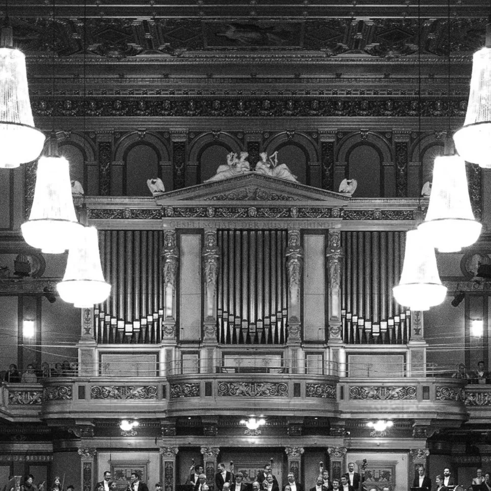 A black and white photograph of an ornate concert hall or cathedral interior with a large pipe organ centered above a balcony.