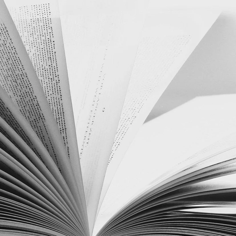A black and white photograph depicting a close-up of a book with its pages fanned out.