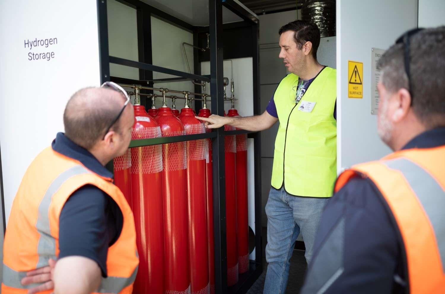 Endua team member speaking with two Pepsico representatives at a hydrogen project deployment with hydrogen storage units