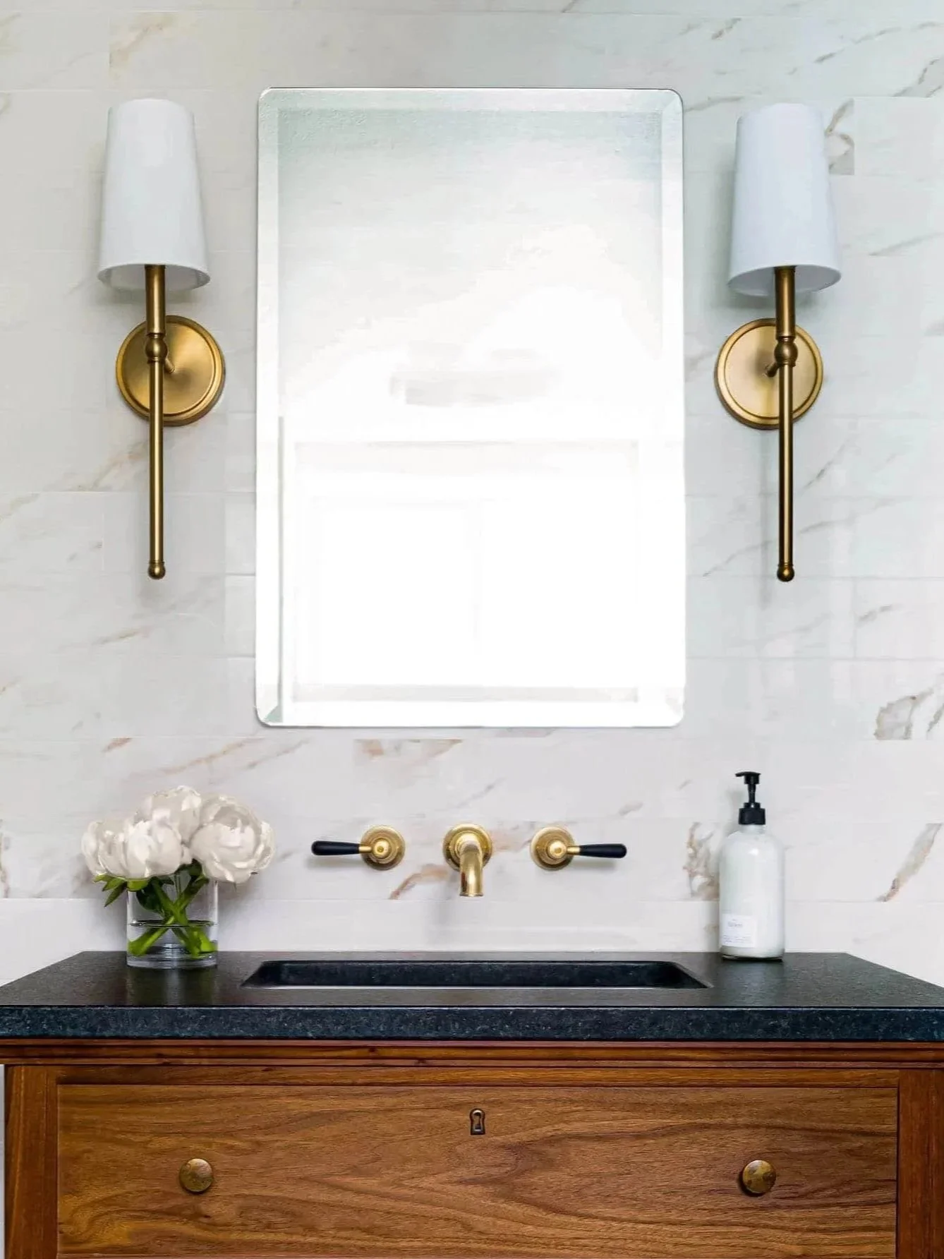 Bathroom vanity with marble backsplash, brass fixtures, and a clean, timeless design.
