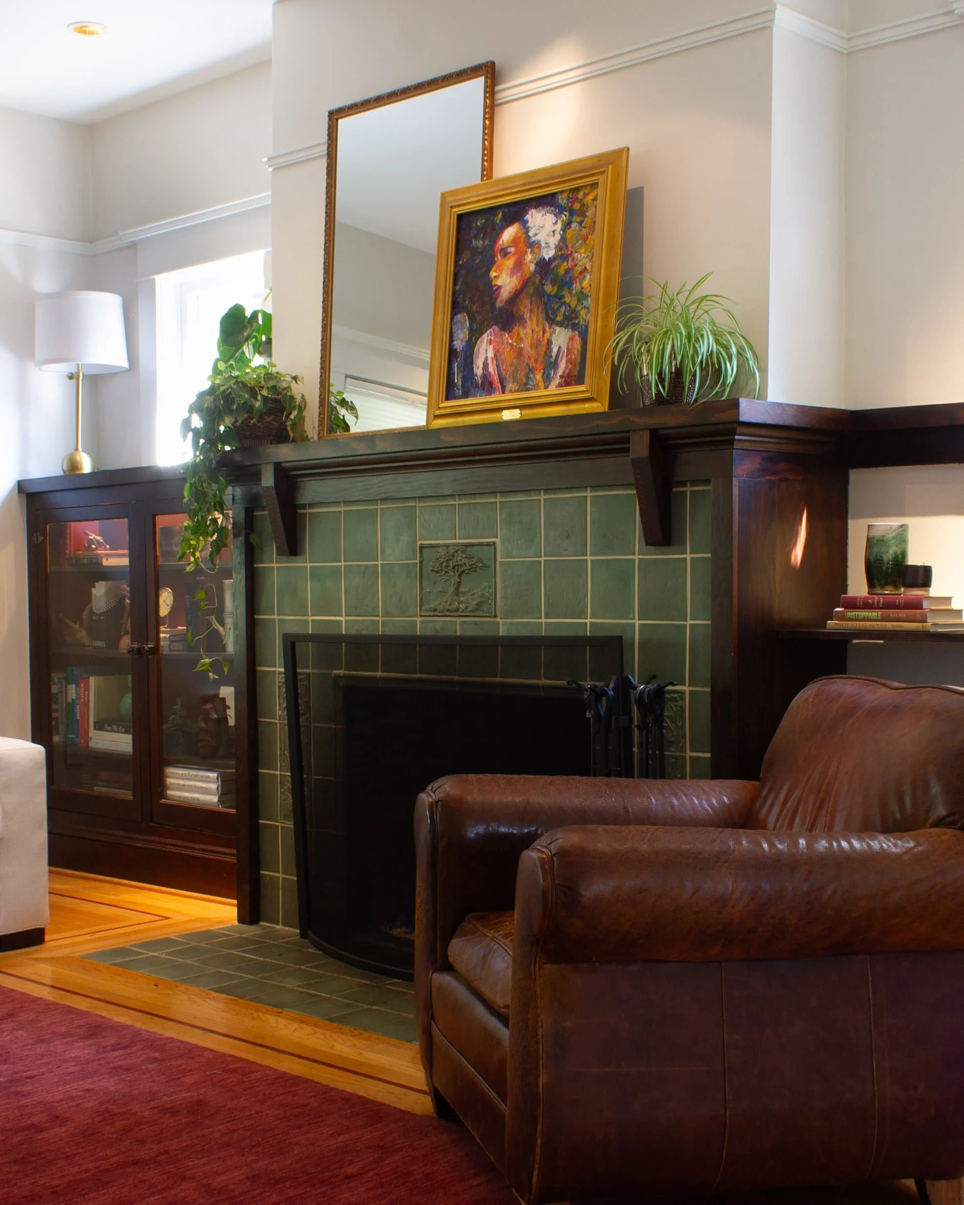 cozy living room with leather armchair, fireplace, painting, and plants