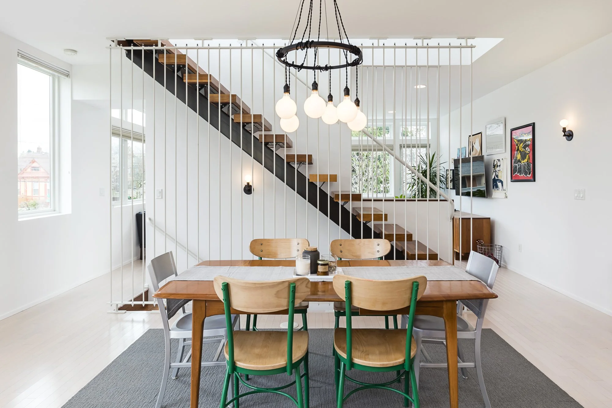 Whole-home interior design in Portland featuring custom dining furniture, modern lighting, and an open staircase with wood and steel details