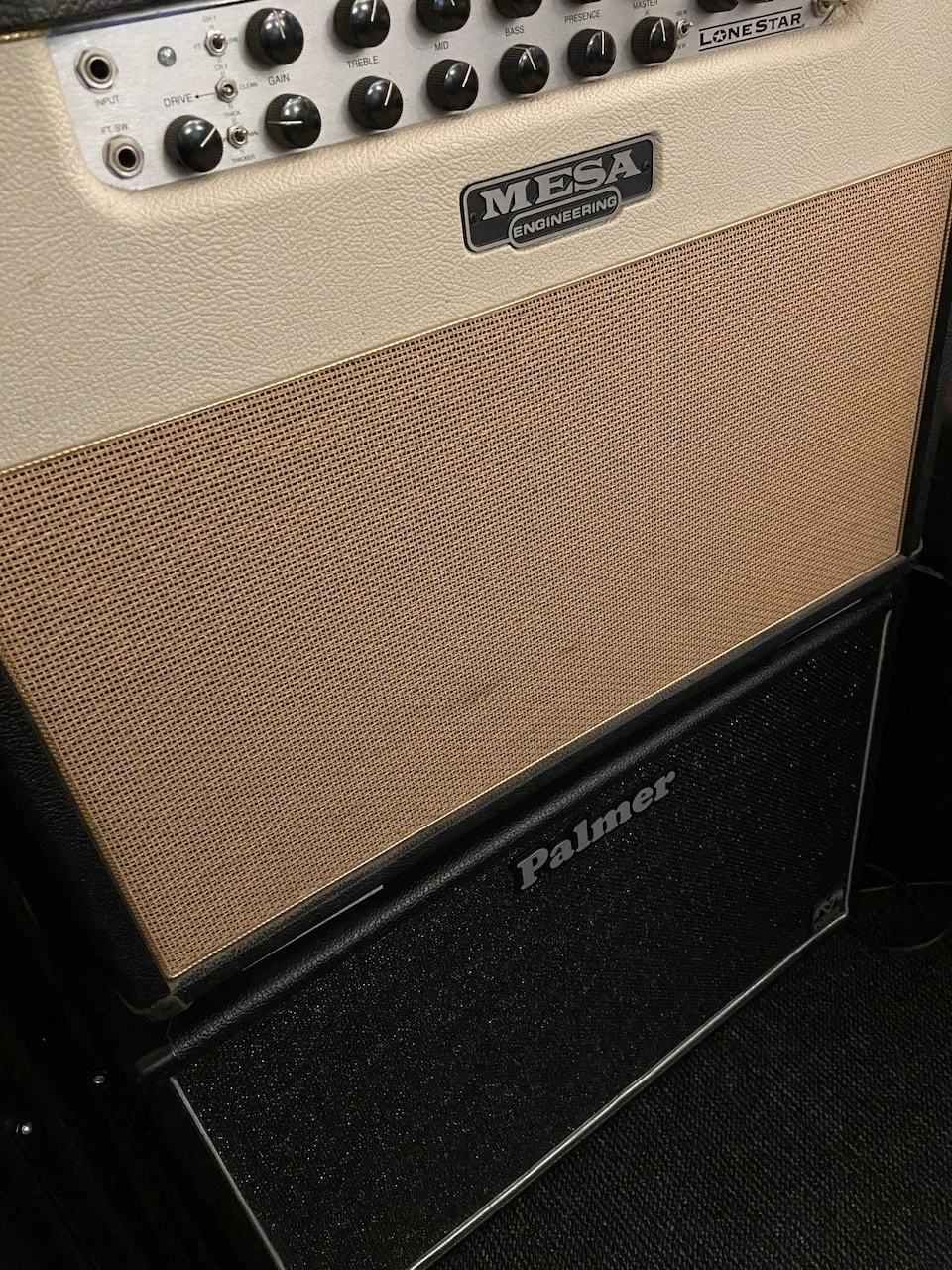 A guitar amplifier stack consisting of a Mesa engineering amplifier head on top of a Palmer speaker cabinet, with various control knobs and input jacks visible on the amp head.