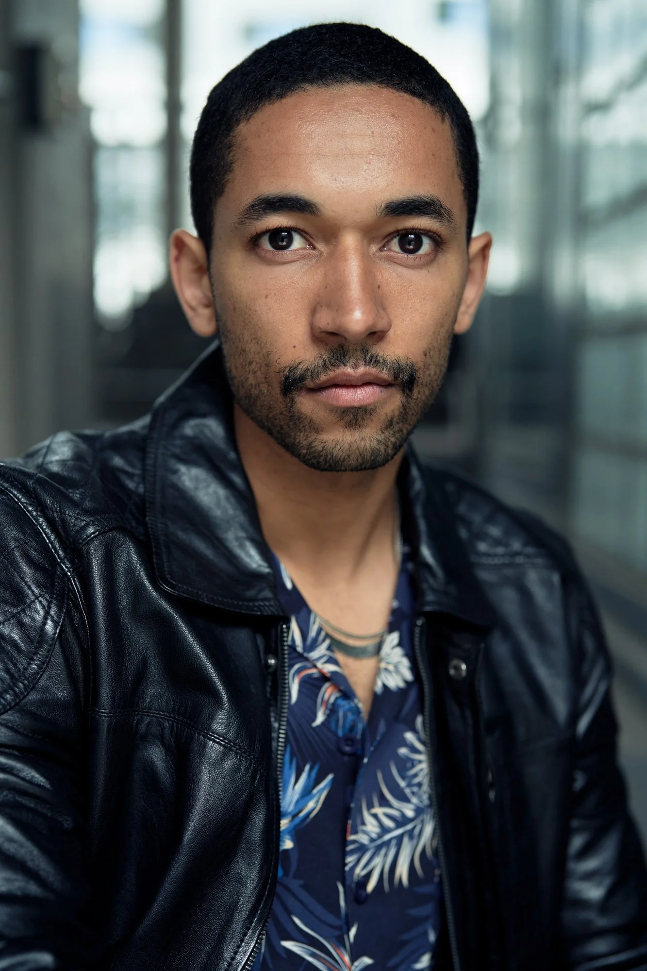 Headshot des Schauspielers Benito Bause in schwarzer Lederjacke über gemustertem Hemd mit direktem Blick, fotografiert von Koszki Photography Berlin.
