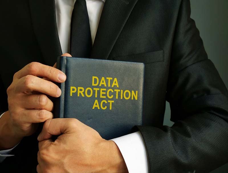 Close-up of a professional in a suit holding a book labeled “Data Protection Act,” representing data privacy and compliance.