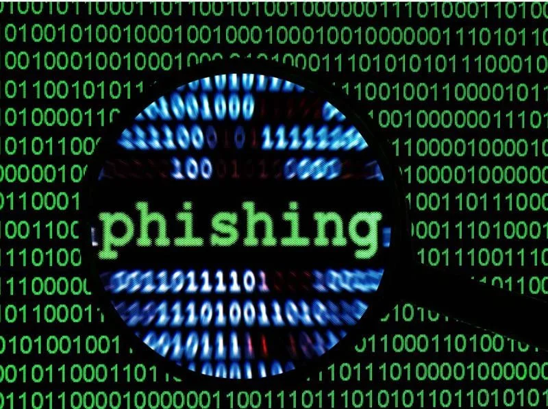 Phishing concept image with magnified word “phishing” over green binary code background, representing cybersecurity threats and email scams.
