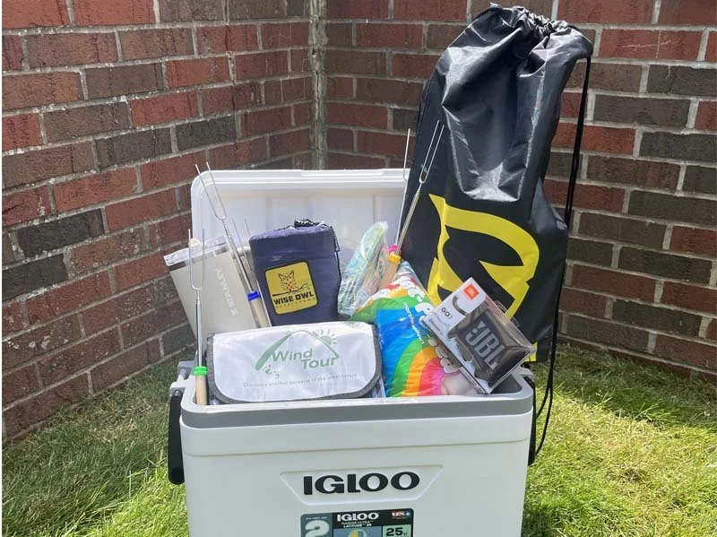 Outdoor adventure prize package with Igloo cooler, camping gear, portable speaker, fishing accessories, and outdoor equipment for a giveaway promotion.