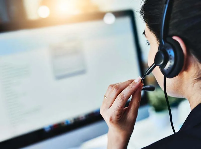 Person wearing a headset while working at a computer, providing customer support or technical assistance.